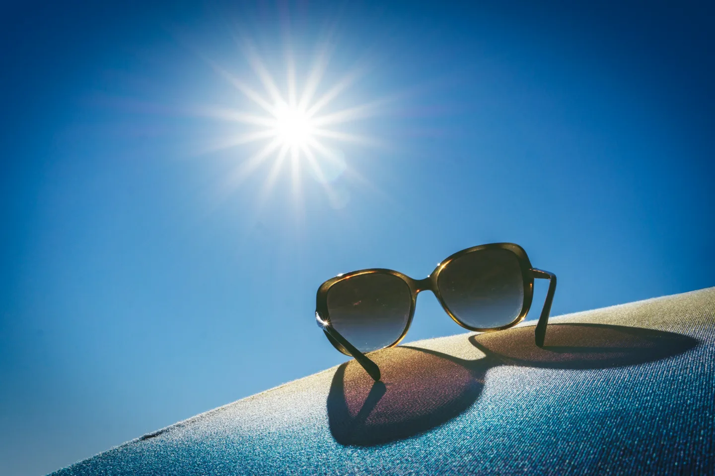Sonnenbrille in praller Sonne vor blauem Himmel