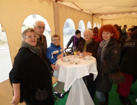 Gäste mit Sektgläsern an einem Stehtisch im Festzelt.
