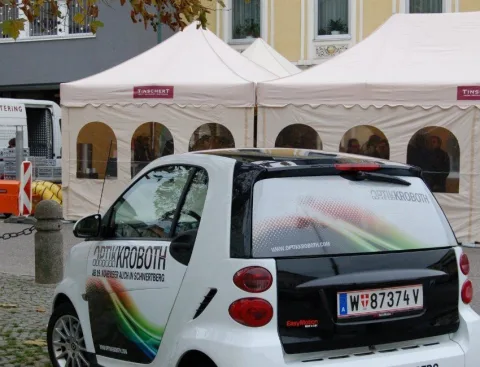 Der beschriftete Firmen-Smart vor den weißen Festzelten am Marktplatz.