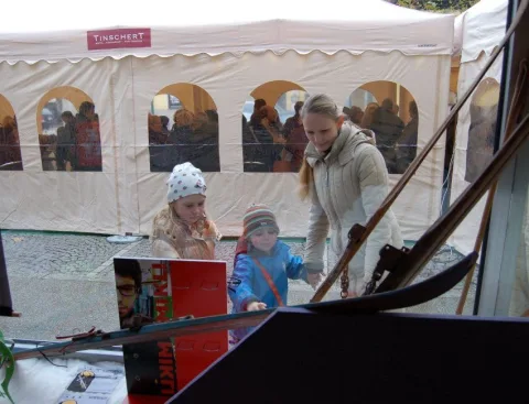 Kinder schauen von draußen durch die Bogenfenster des Festzelts.
