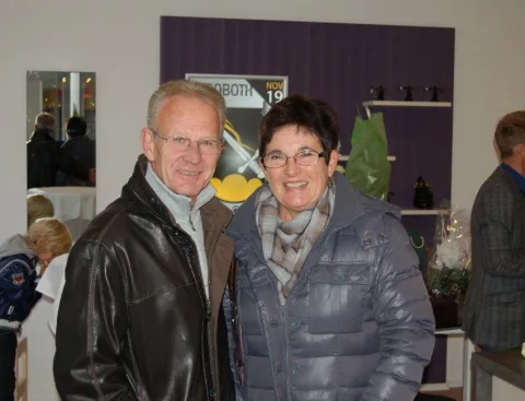 Ein Paar im Verkaufsraum vor der violetten Wand mit dem Kroboth-Wappen.