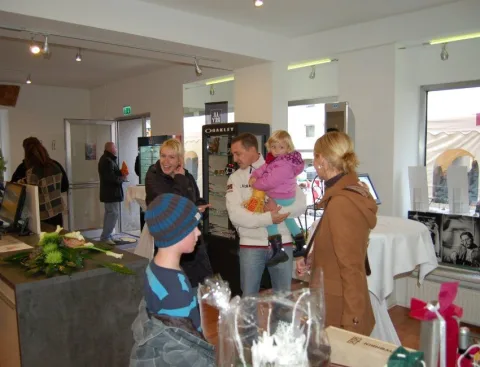 Gäste mit Kindern und Blumengeschenken im Eingangsbereich.