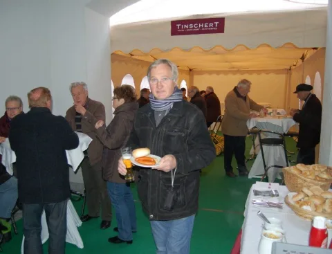 Ein Gast trägt einen Teller mit Gebäck durch das Festzelt.