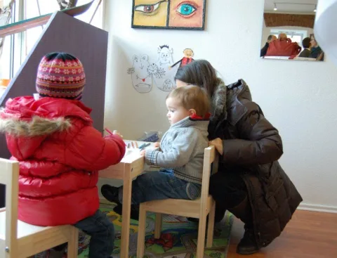 Zwei Kinder malen an einem kleinen Tisch in der Kinderecke.