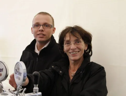 Ein Mitarbeiter zapft Bier, daneben eine Besucherin.