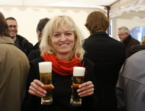 Eine Frau hält zwei Gläser Bier in die Kamera.