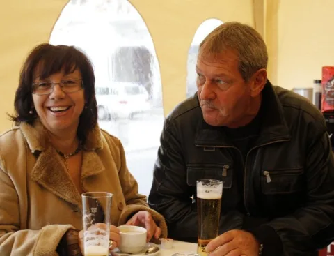 Ein Paar mit Bier an einem Tisch am Zeltfenster.