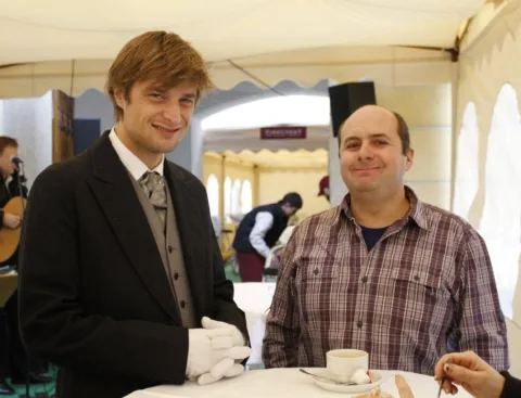 Ein Mitarbeiter mit weißen Handschuhen serviert einem Gast Kaffee.