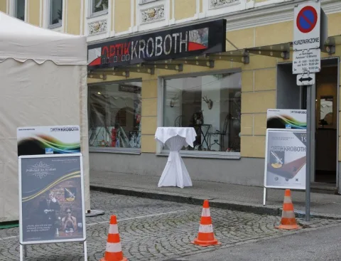 Das Geschäft von außen mit Firmenschild, Aufstellern und Festzelt daneben.