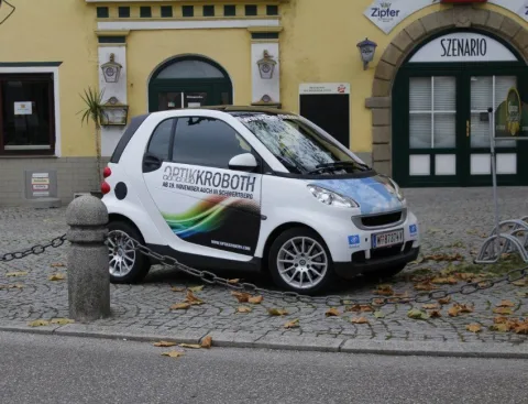 Der beschriftete Firmen-Smart am Straßenrand vor dem Geschäft.