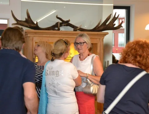 Gäste vor einem alten Holzschrank mit Geweih