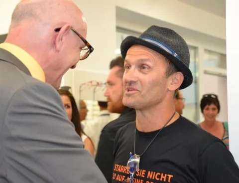 Zwei Gäste im Gespräch, einer mit Hut