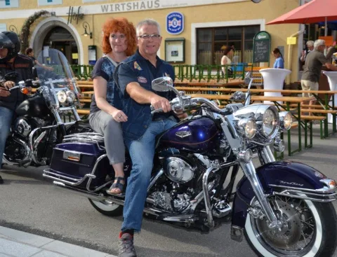 Zwei Personen auf einem Motorrad vor einem Wirtshaus