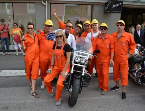 Eine Gruppe in orangen Overalls und Helmen neben einem Motorrad