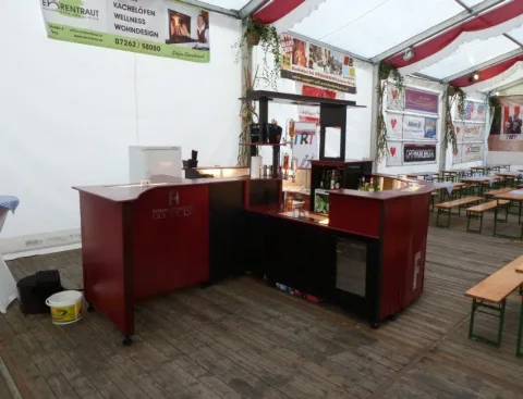 Die aufgebaute, noch unbesetzte Bar im Festzelt, davor Bierbankgarnituren