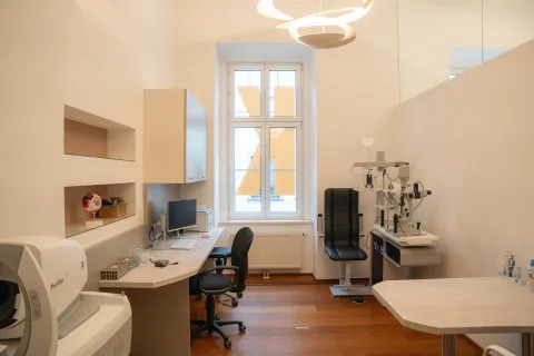 Untersuchungsraum am Sprossenfenster, mit Refraktionsgerät, Bildschirmarbeitsplatz, Behandlungsstuhl und Spaltlampe