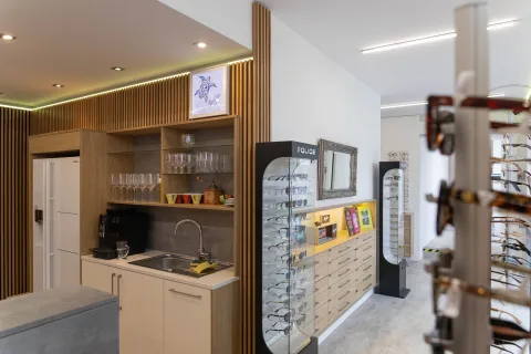Die Kaffeeecke hinter der Theke mit Regalen, Vitrine und einem Drehständer mit Brillen