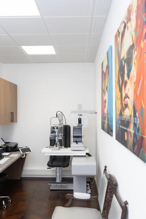 Spaltlampe und Refraktionsgerät im Untersuchungsraum, rechts ein Pop-Art-Bild