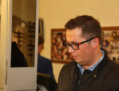Ein Mann mit Brille steht vor einem Spiegel