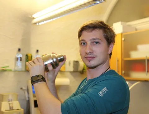 Ein Mann in einem grünen Hemd hält einen Shaker