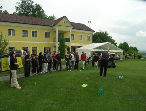 Teilnehmer auf der Wiese vor dem gelben Clubhaus