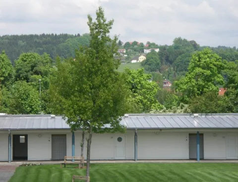 Der Platz mit Bäumen und flachem Gebäude