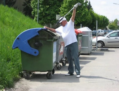 Ein Mann schiebt Mülltonnen einen Weg entlang