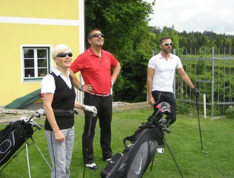 Drei Teilnehmer mit Golftaschen auf der Wiese