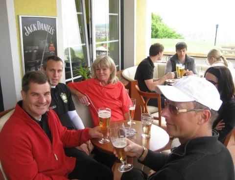 Gäste mit Gläsern an einem Tisch im Clubhaus