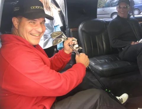 Ein Mann mit Kappe und Golfschläger in der Limousine
