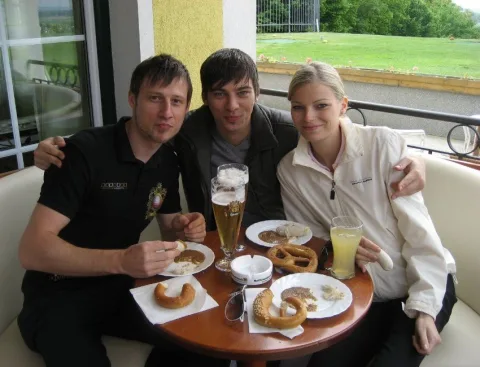 Drei Gäste an einem Tisch mit Brezen und Getränken