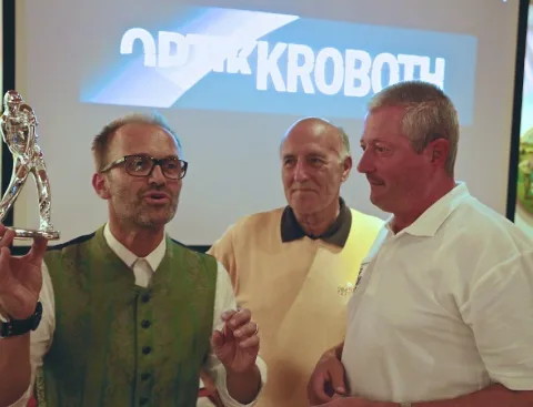 Ein Preisträger hält einen Pokal hoch