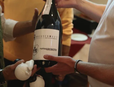 Eine Flasche mit Optik-Kroboth-Etikett wird überreicht