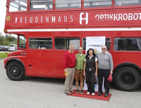 Drei Teilnehmer auf rotem Teppich vor dem Bus