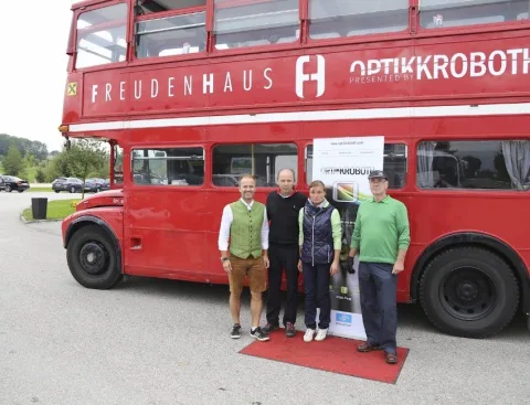 Vier Teilnehmer auf rotem Teppich vor dem Bus