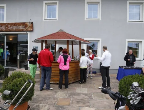 Gäste an einem Stand vor einem Haus