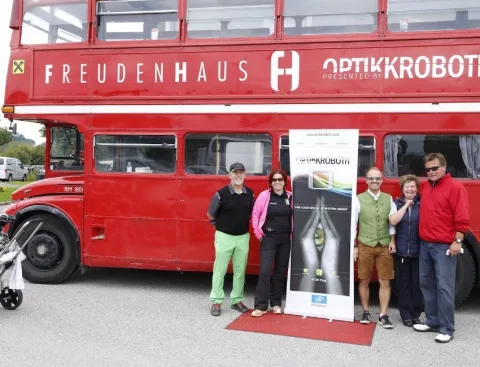 Vier Teilnehmer auf rotem Teppich vor dem Bus