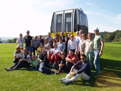 Gruppenbild der Teilnehmer auf der Wiese vor einer Gondel