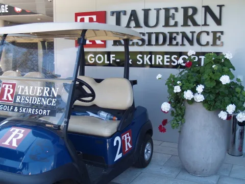 Ein Golfwagen vor dem Schild des Resorts