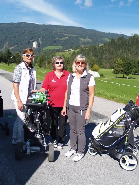 Drei Teilnehmerinnen mit ihren Golftaschen