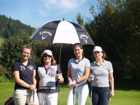 Vier Teilnehmerinnen unter einem Golfschirm