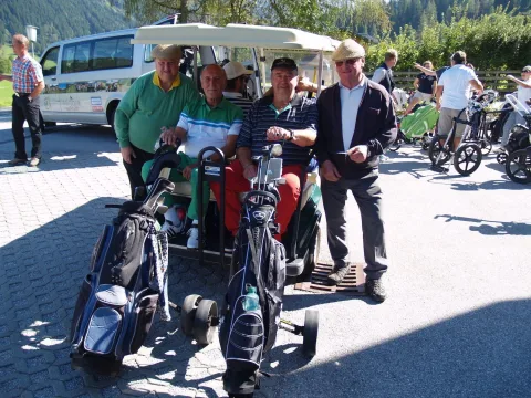 Teilnehmer mit Golfwagen vor dem Clubhaus