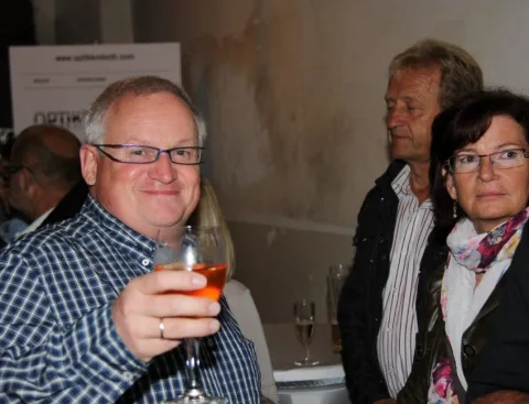 Ein Gast mit Glas und zwei weitere Gäste