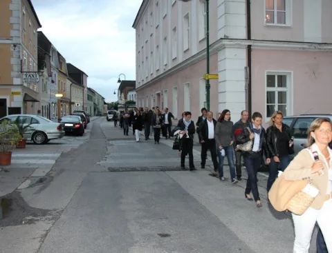 Besucher gehen eine Straße entlang, rechts historische Häuser