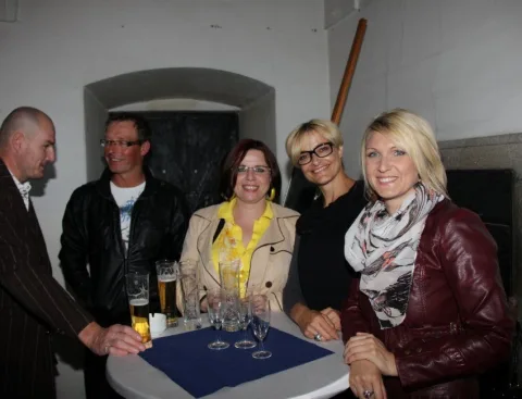 Vier Gäste an einem Stehtisch mit Gläsern
