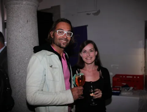 Ein Mann und eine Frau mit Gläsern unter einem Gewölbebogen