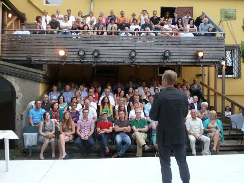 Ein Mann spricht vor dem voll besetzten Zuschauerraum