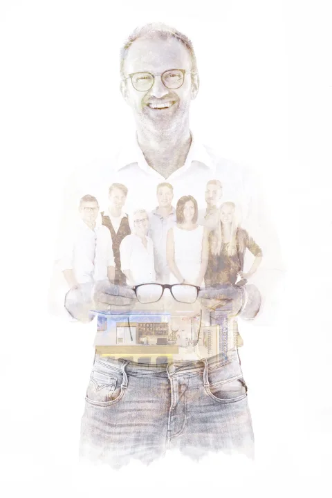 Doppelbelichtung: Ein Mann hält eine Brille in die Kamera, in deren Gläsern sich das Team spiegelt