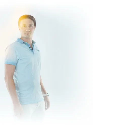 Ein Mitarbeiter im hellblauen Poloshirt steht vor weißem Hintergrund