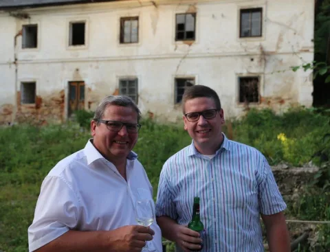 Zwei Gäste mit Getränken vor dem Gutshof